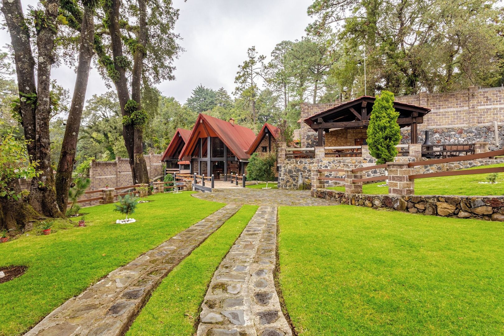 A rustic lodge with a stone pathway leading to a wooden deck and a stone wall.