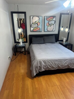 A bedroom with a bed, a nightstand, a mirror, and abstract art on the wall. - Cozy 1-bedroom apartment in delightful Houston with AC in the Midtown Area (Houston)
