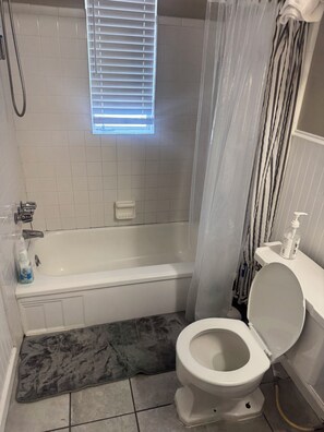 A bathroom with a bathtub, toilet, and shower curtain. - Cozy 1-bedroom apartment in delightful Houston with AC in the Midtown Area (Houston)