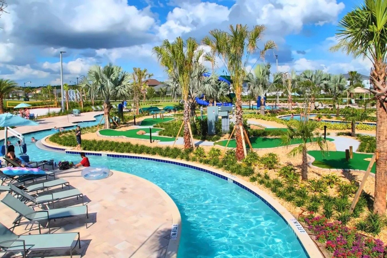 A swimming pool with lounge chairs, palm trees, and a miniature golf course.