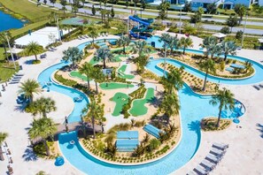 An aerial view of a resort with multiple swimming pools, a water slide, and a golf course. - Lake View 2BR Condo Near Disney (Kissimmee)
