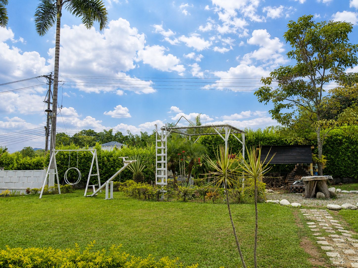 A grassy outdoor area with a swing set, a ladder, and a small garden.
