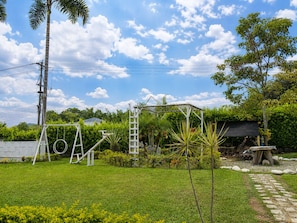 A grassy outdoor area with a swing set, a ladder, and a small garden. - New Listing (La Tebaida)