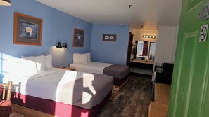Habitación de hotel con dos camas, un escritorio, un espejo y cuadros en la pared.