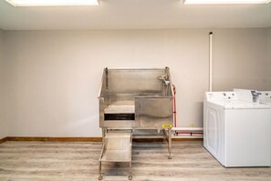 Une buanderie équipée d’un lave-linge et d’un sèche-linge en acier inoxydable, d’un évier en métal et d’un plancher en bois.