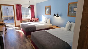 Une chambre d’hôtel avec deux lits, une table à manger et une vue sur l’extérieur.
