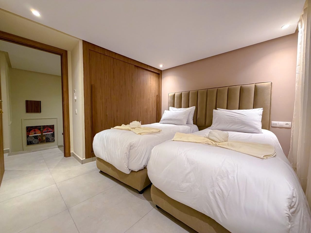 Habitación de hotel con dos camas, un armario de madera y un cuadro en la pared.