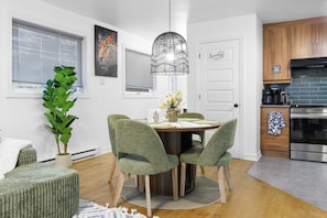 A modern kitchen with a dining area, wooden cabinets, a built-in oven, and a dining table with chairs. - The extravagant minimalist 3 (Gatineau)