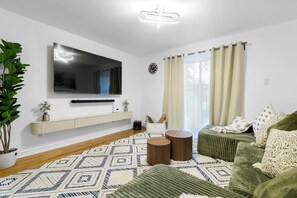 A modern living room with a flat-screen TV, a sofa, a coffee table, and a patterned rug. - The extravagant minimalist 3 (Gatineau)