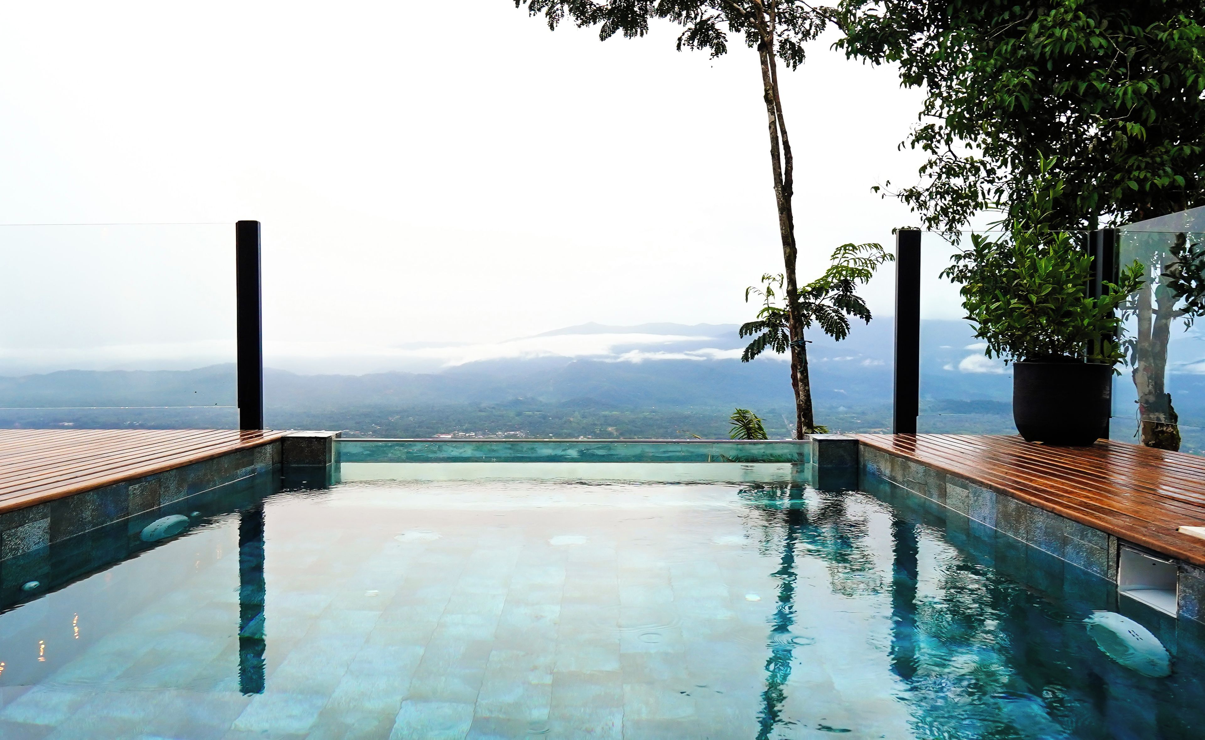 Una piscina infinita con vistas a montañas distantes y un cielo nublado.