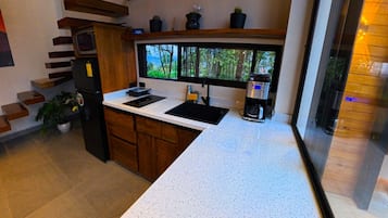 A modern kitchen with a white countertop, built-in appliances, and a window with a view of trees.