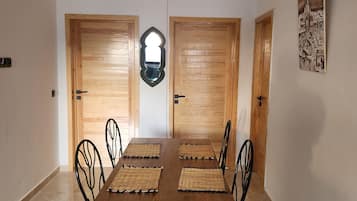 Zona pranzo con tavolo e sedie in legno, uno specchio e un quadro appeso al muro.