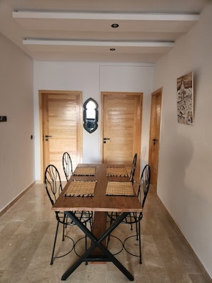 Zona pranzo con tavolo e sedie in legno, uno specchio e un quadro appeso al muro.