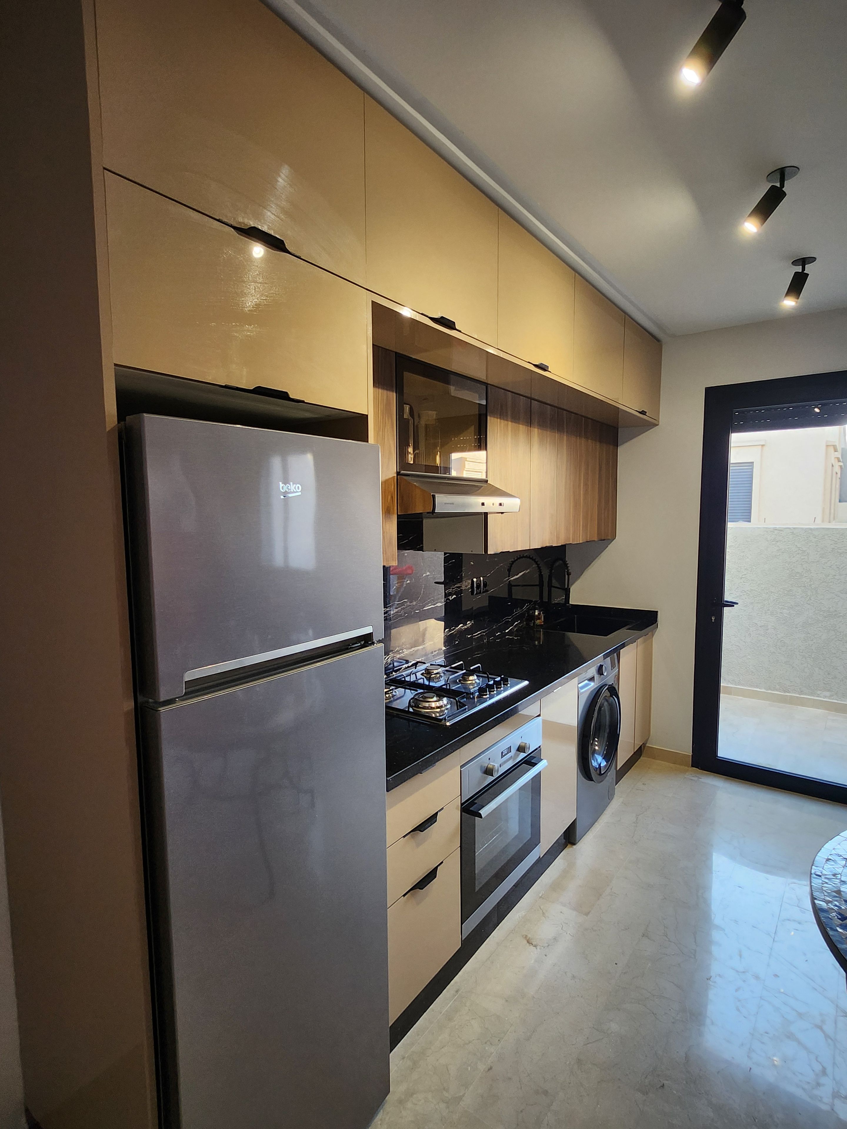 A modern kitchen with a refrigerator, stove, oven, and washing machine.
