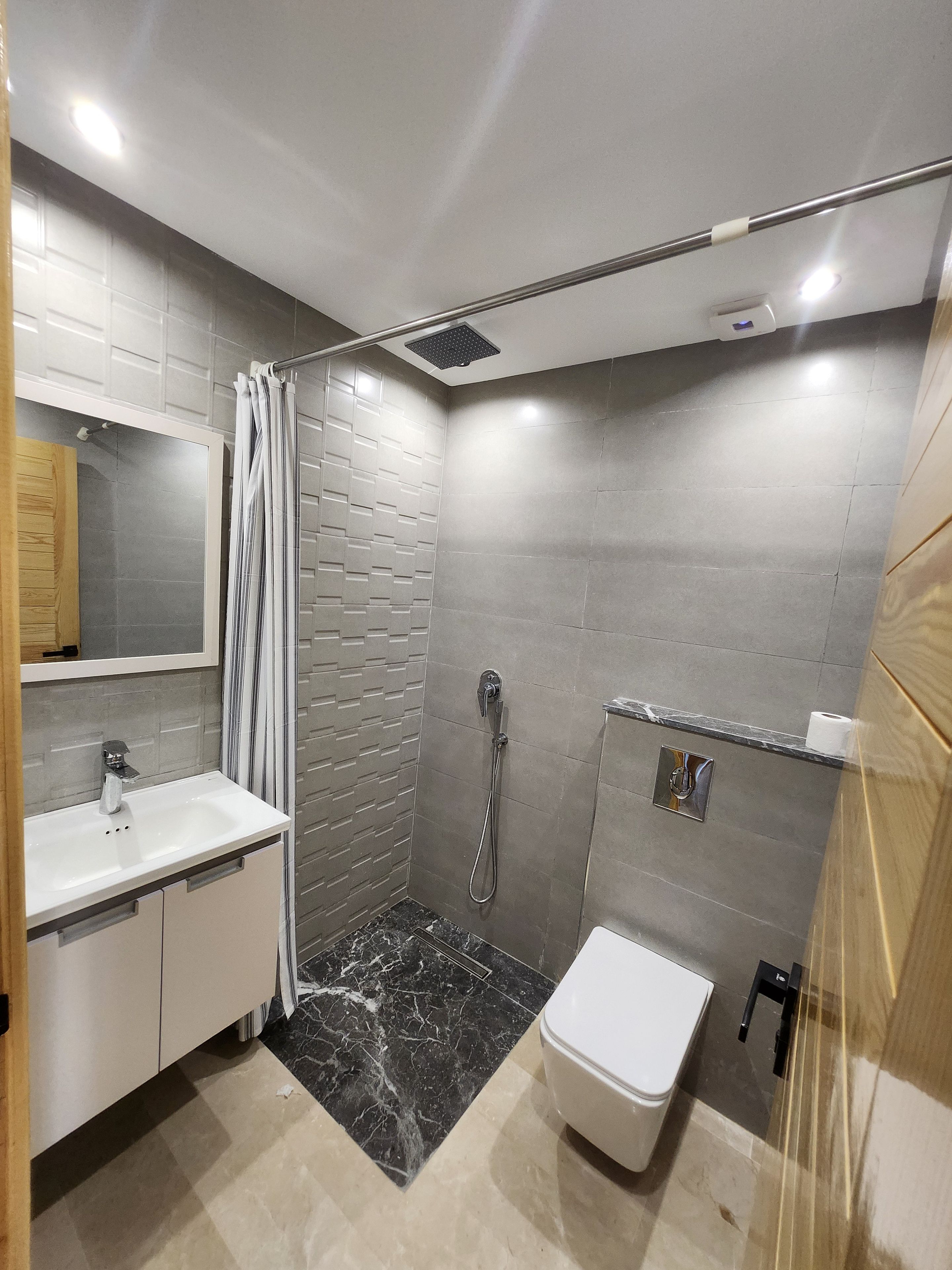 A modern bathroom with a shower, toilet, and sink.