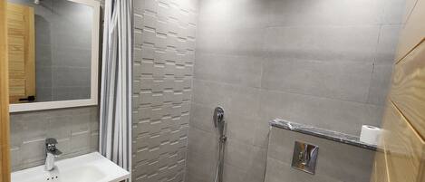 A modern bathroom with a shower, toilet, and sink.