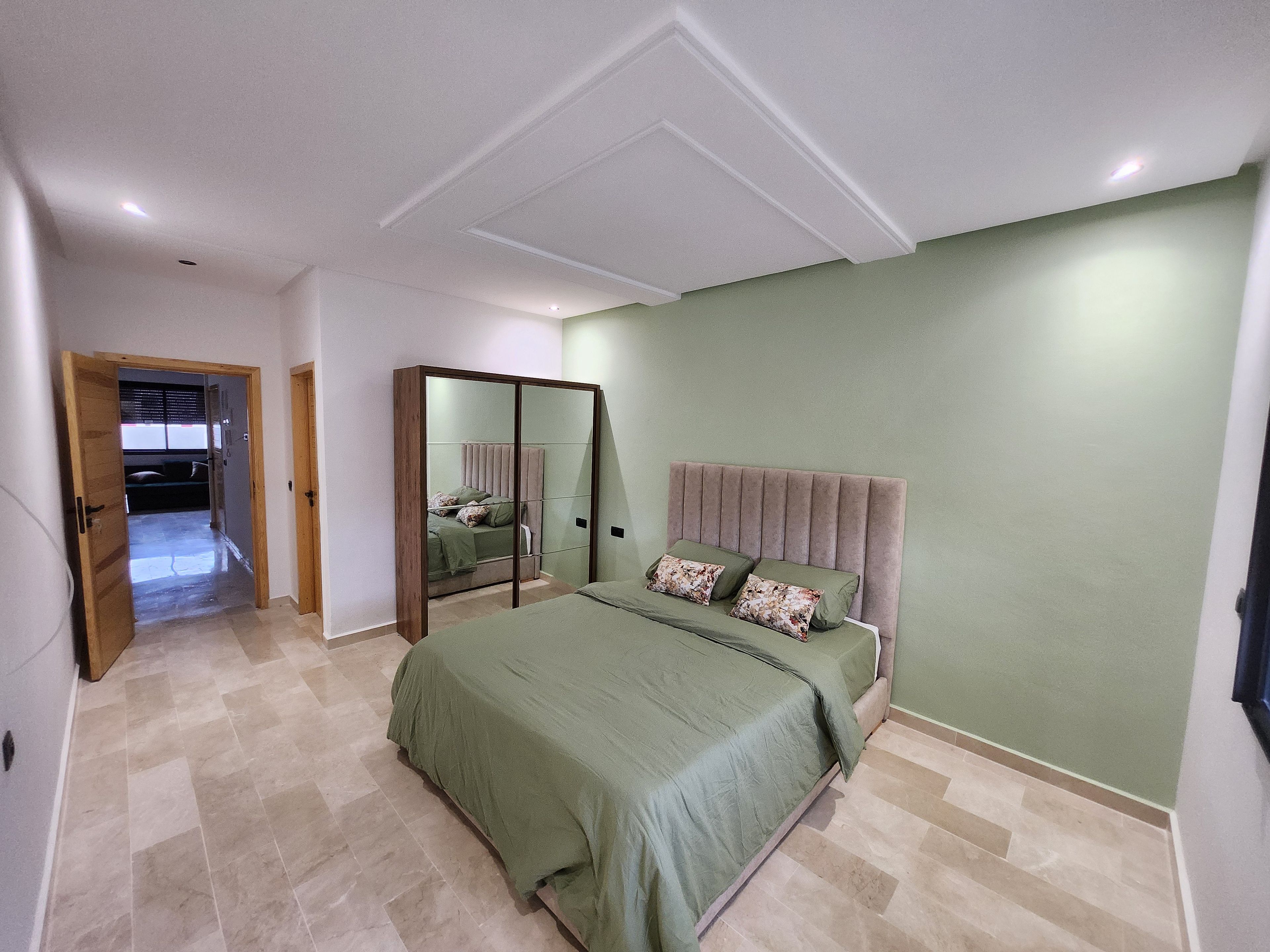 Una camera da letto con un letto, uno specchio e una porta che dà su un'altra stanza.