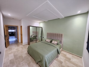 Una camera da letto con un letto, uno specchio e una porta che dà su un'altra stanza.
