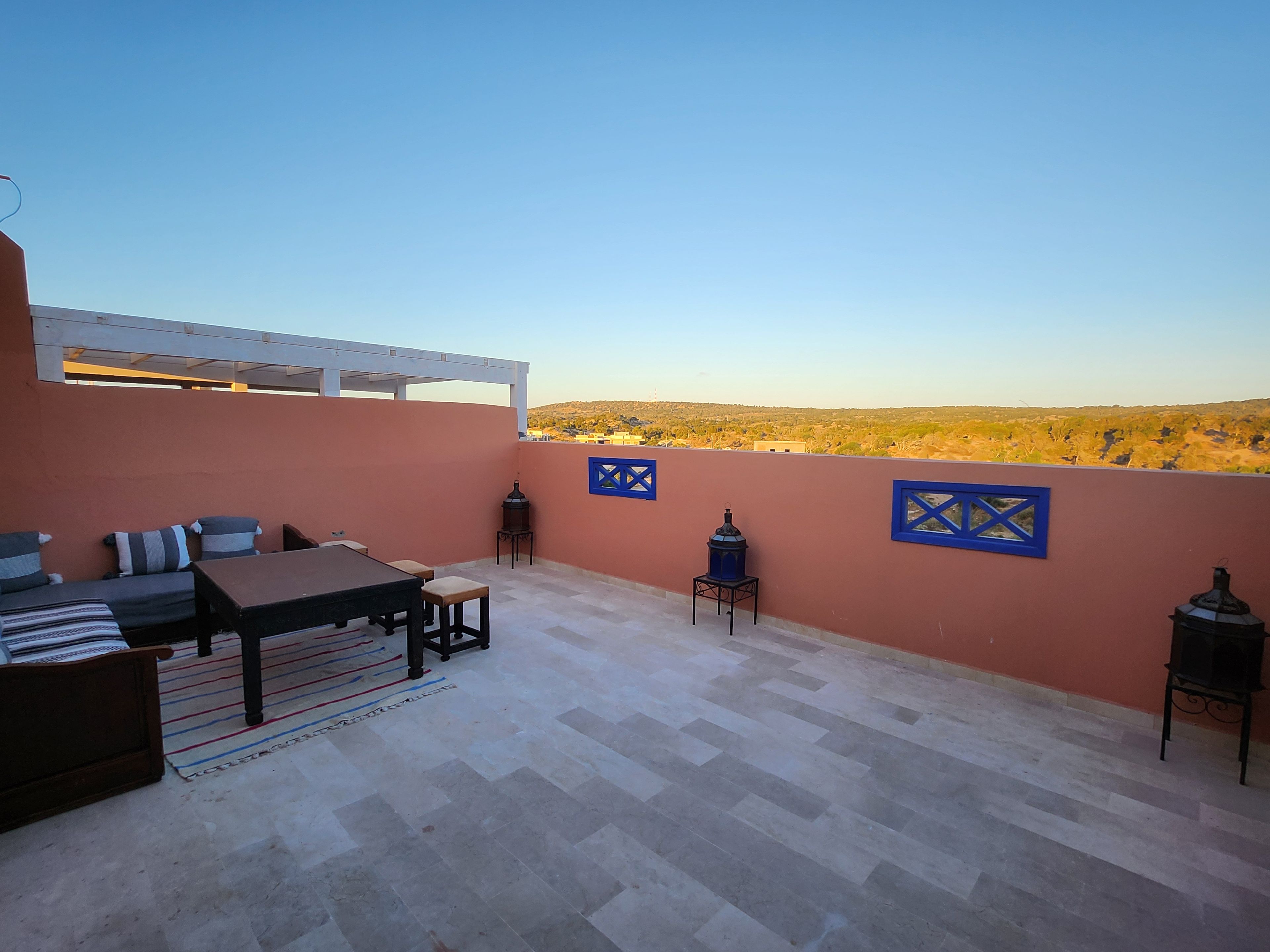 Una terrazza sul tetto con un tavolo e sedie, un divano e decorazioni a parete.