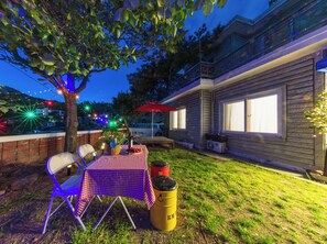 An outdoor patio with a table set for dining, a red umbrella, and a tree providing shade. - Private 3-bedroom House w/ Scenic Mt. View & Private Garden in Historic Jongro (Seoul)