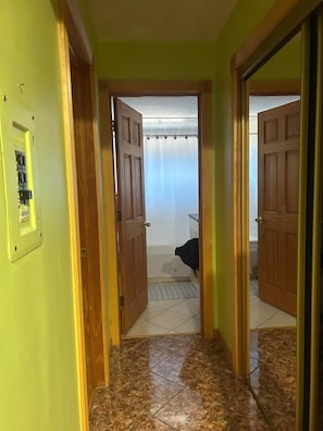Ein Flur mit Holztüren, die zu einem Badezimmer mit Duschvorhang führen.