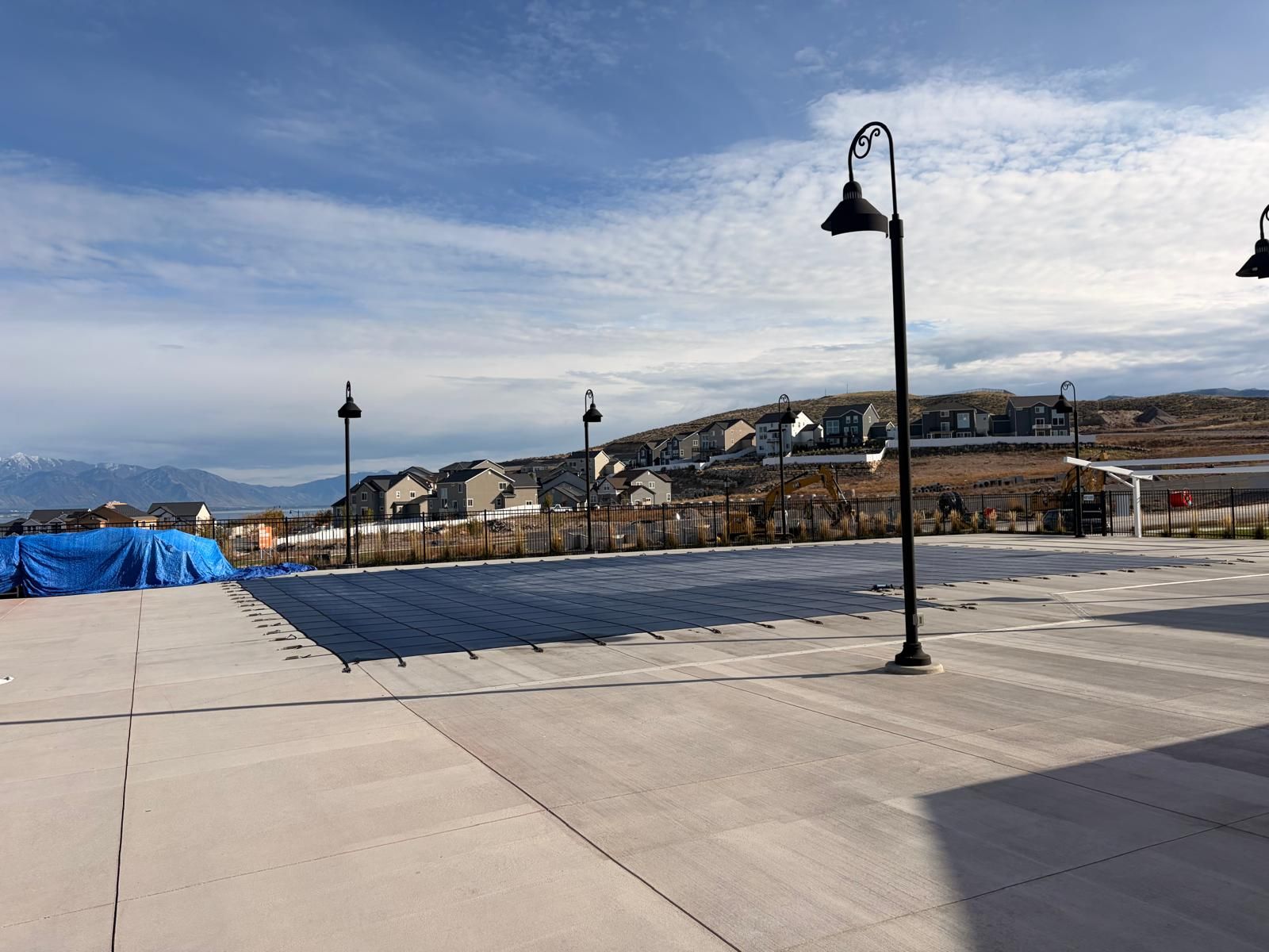 A paved outdoor area with street lamps and a view of residential buildings in the background.