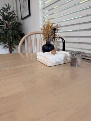 A wooden table with a folded cloth, a small vase with dried plants, and salt and pepper shakers. - "The Yellowbelle" Pinecraft N. - Sarasota 2b/1b Private Apartment w/ Shared Wall (Sarasota)