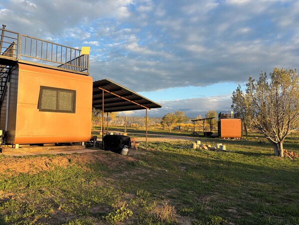 A modern building with a covered outdoor area, a fenced yard, and a view of distant mountains.