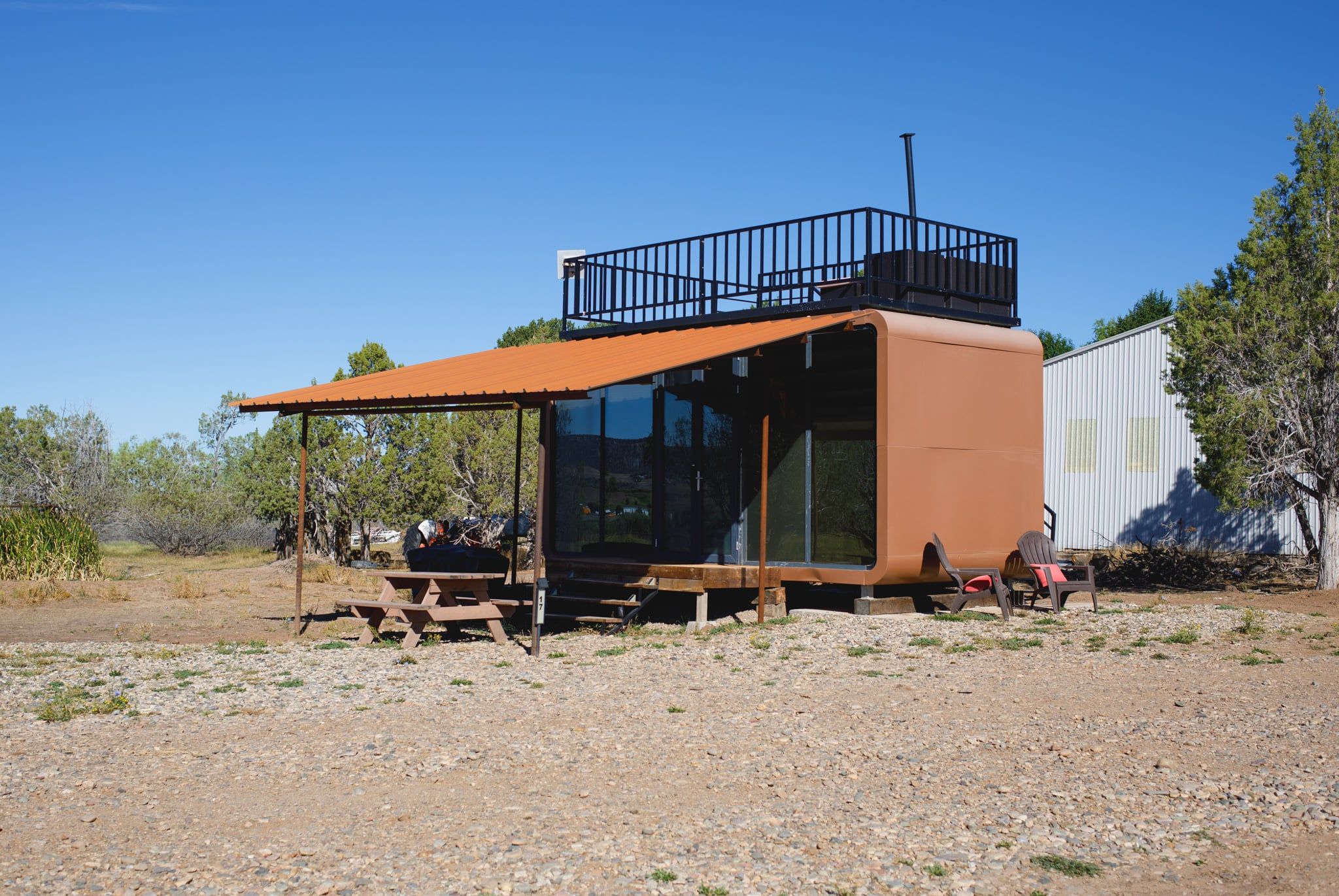 Un chalet rustique doté d’un patio couvert, d’une petite terrasse et d’une table de pique-nique.