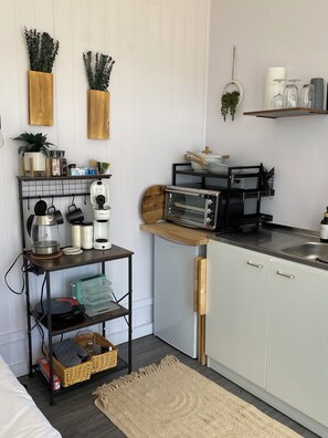 A modern kitchen with white cabinetry, a wooden countertop, a built-in toaster oven, and a small dining area with a bench.