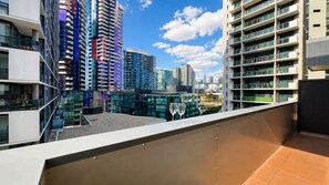 A rooftop terrace with a view of modern high-rise buildings. - Stylish Apt | King Bed, Balcony, Free Car Park & Indoor Swimming Pool (Docklands)