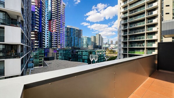 A rooftop terrace with a view of modern high-rise buildings. - Stylish Apt | King Bed, Balcony, Free Car Park & Indoor Swimming Pool (Docklands)