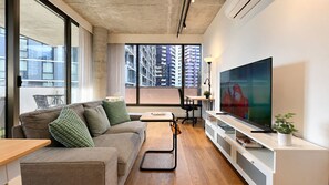 A modern living room with a sofa, TV, and a dining area. - Stylish Apt | King Bed, Balcony, Free Car Park & Indoor Swimming Pool (Docklands)