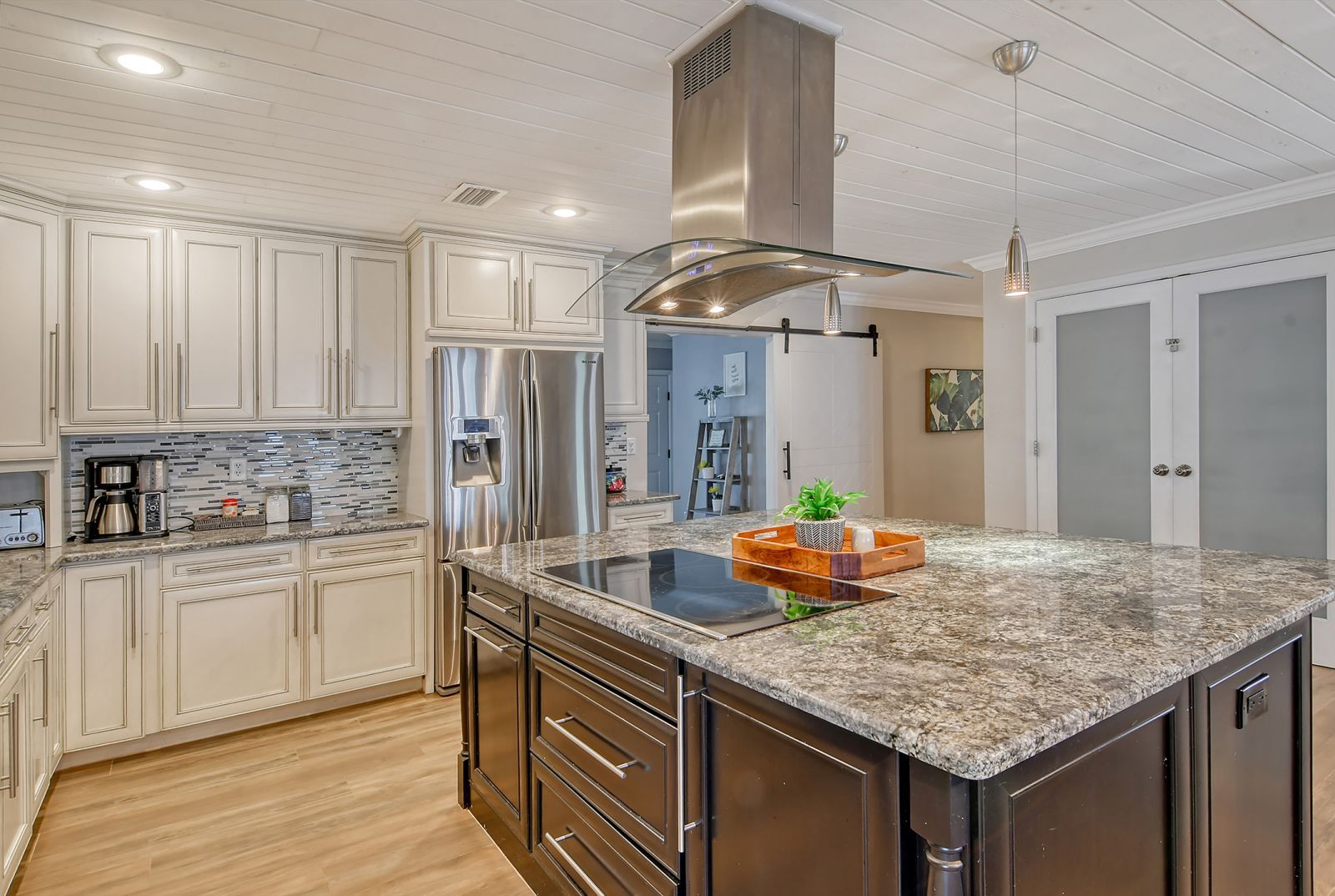 A modern kitchen with a central island, stainless steel appliances, and a backsplash.