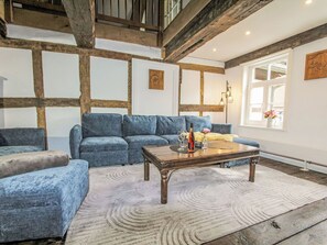 Een woonkamer met een blauwe bank, een houten salontafel en een vloerkleed met dessin.