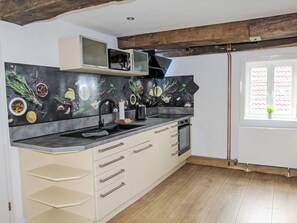 Een keuken met een modern ontwerp, met een zwarte achterwand met afbeeldingen van eten, een inbouwoven en een raam met uitzicht.