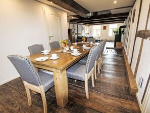 Un coin repas avec une table en bois dressée pour quatre personnes, entourée de chaises rembourrées ornées de clous en métal.