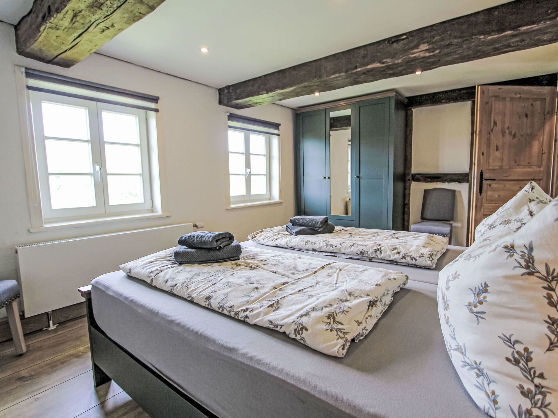 Een slaapkamer met twee bedden, een radiator, een raam en een kledingkast.