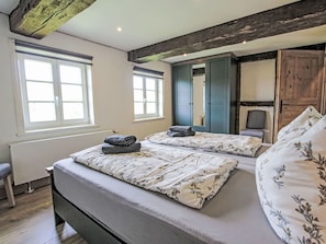 Une chambre avec deux lits, un radiateur, une fenêtre et une armoire.