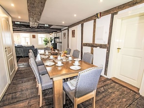 Comedor con mesa de madera dispuesta para seis personas, rodeado de sillas tapizadas.