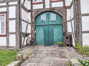 Ein traditionelles Fachwerkhäuschen mit einer grünen Tür, einem Schubkarren und einem kleinen Garten.