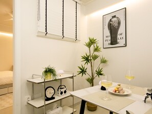 Een moderne badkamer met een witte wasbak, een spiegel, een handdoekrek en een plank met een klok en een radio.