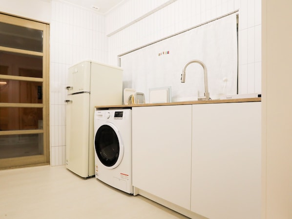 Een kleine keuken met een wasmachine, een magnetron en een spoelbak.