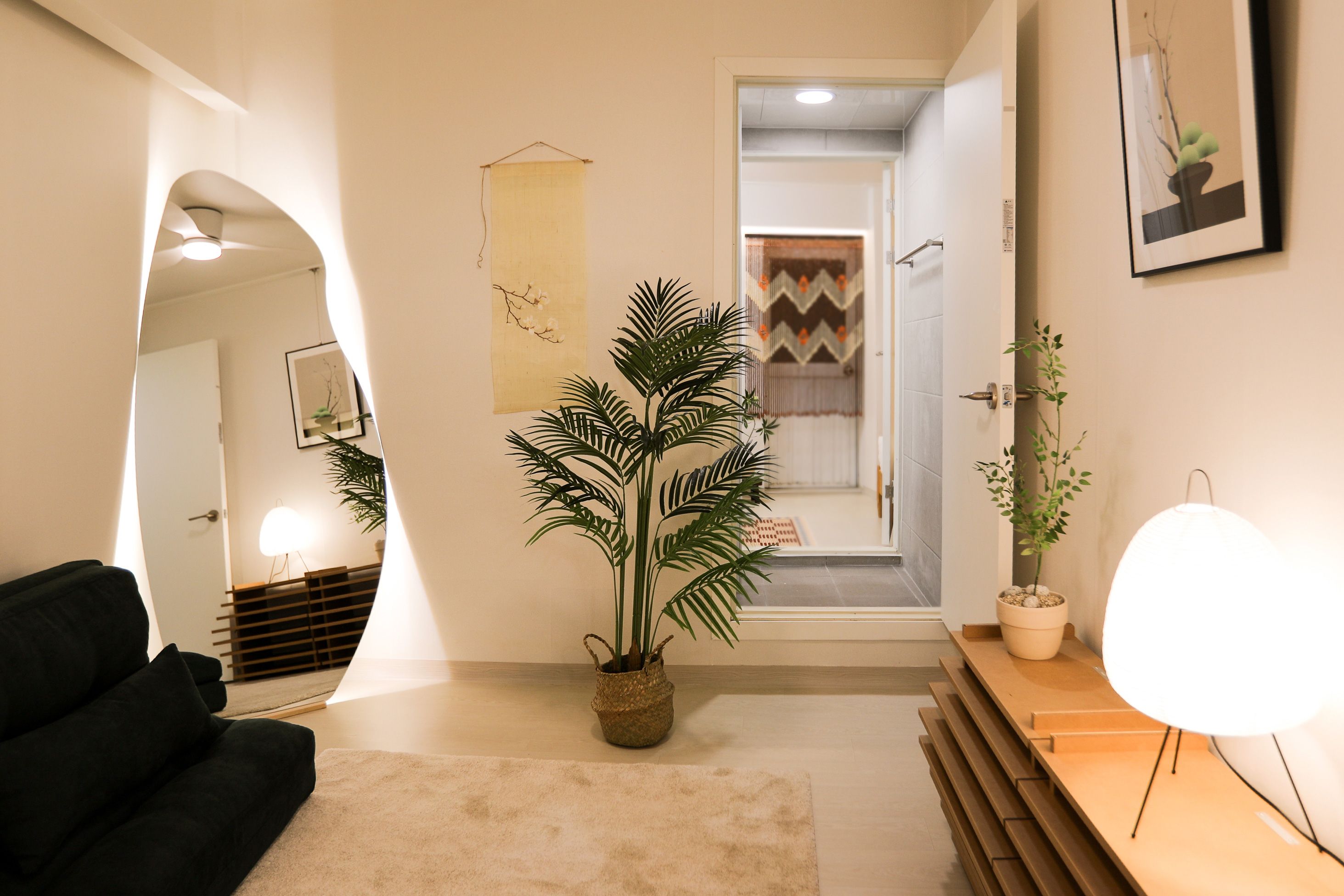 A modern interior with a sofa, a potted plant, a lamp, and a framed picture on the wall.