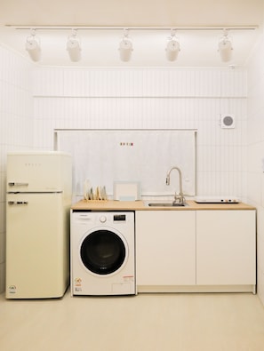Une cuisine de taille réduite équipée d’un lave-linge, d’un réfrigérateur et d’un évier.