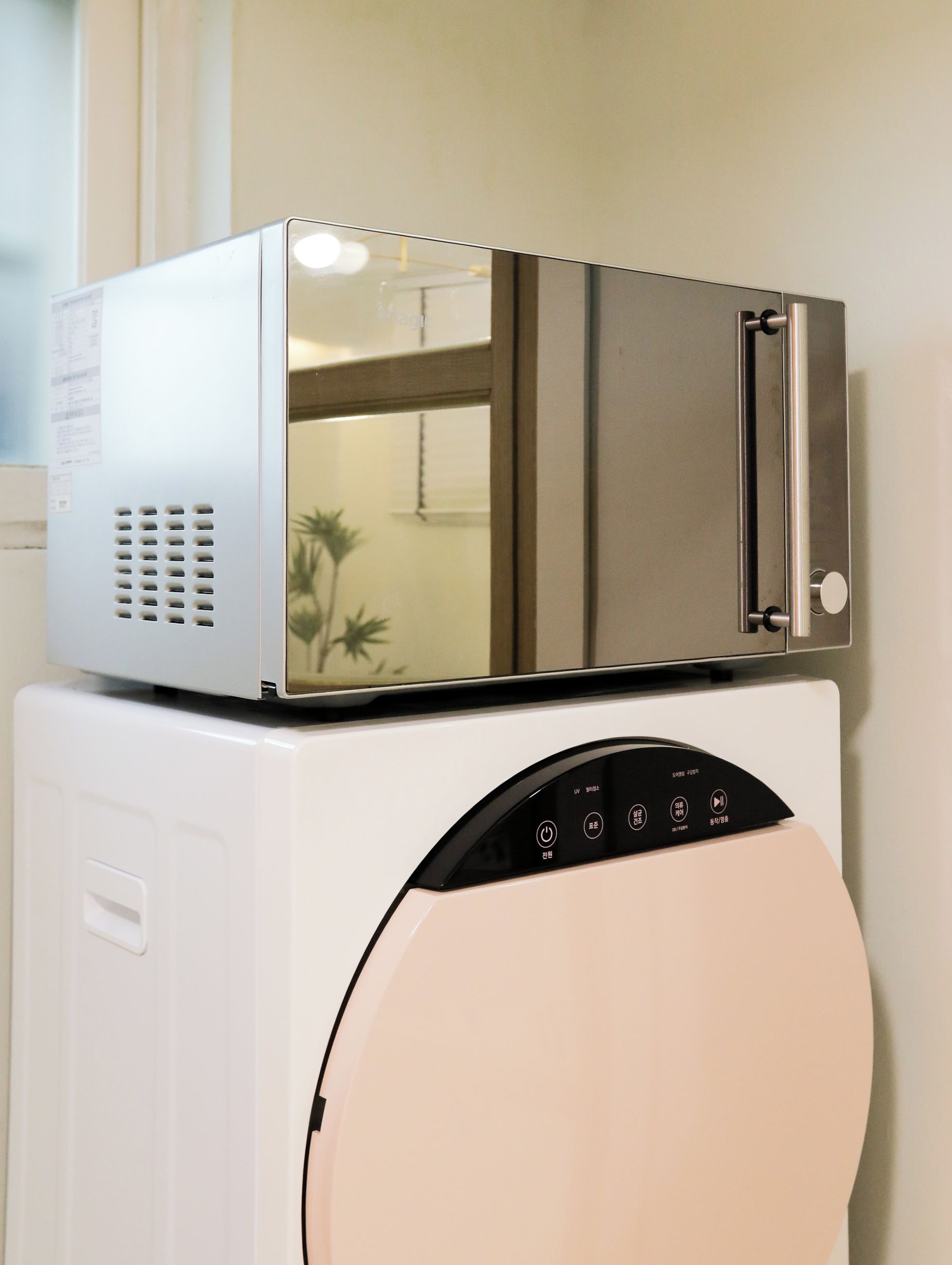 A compact washer and dryer unit with a control panel and a vent.