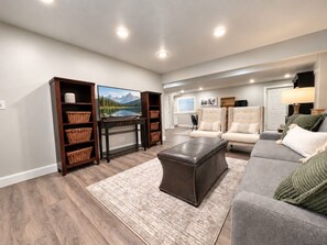 Ein Wohnzimmer mit einer Couch, einem Hocker und einer Unterhaltungsanlage mit Körben.