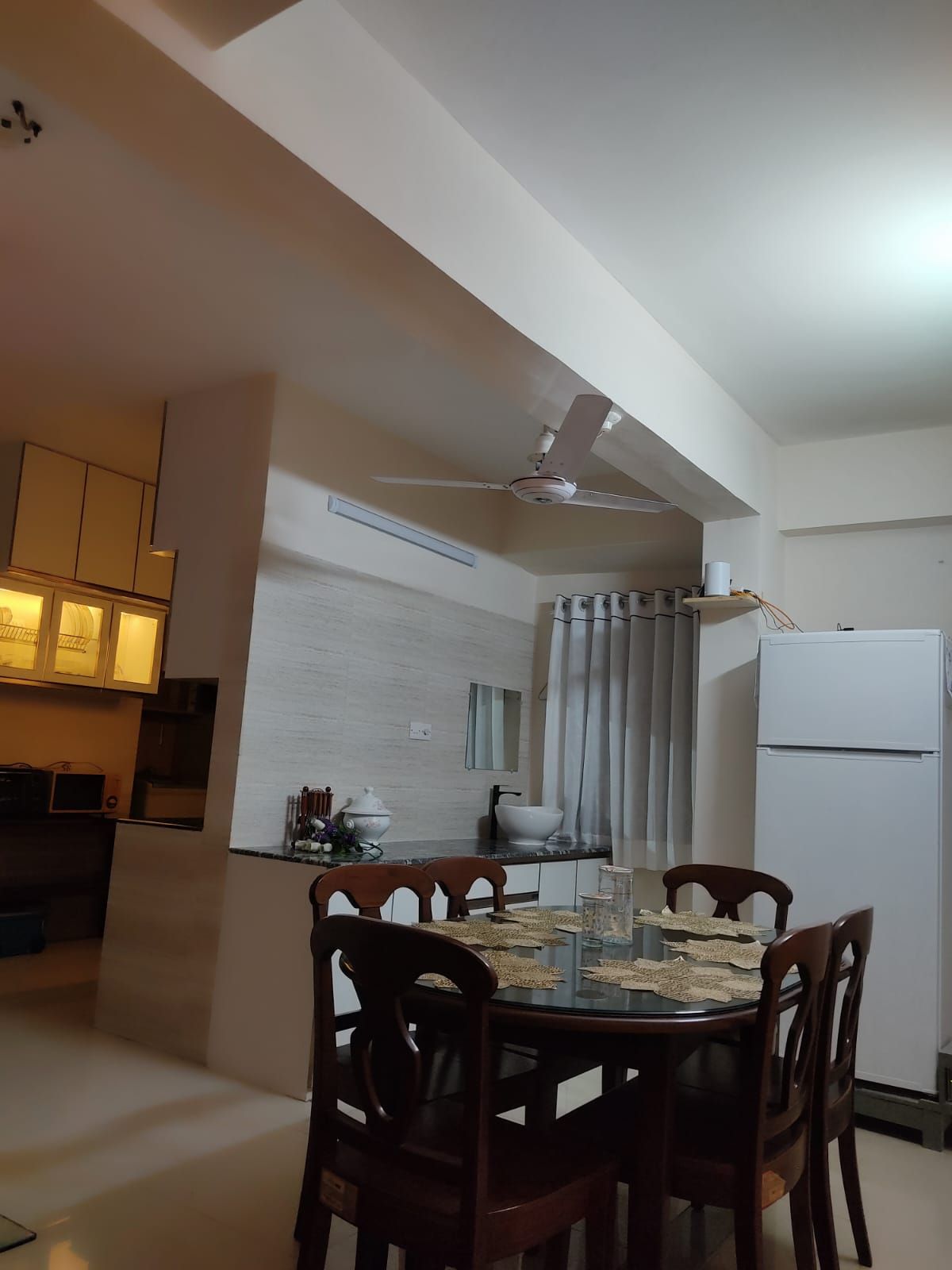 A compact kitchen with a dining area, a ceiling fan, and a refrigerator.