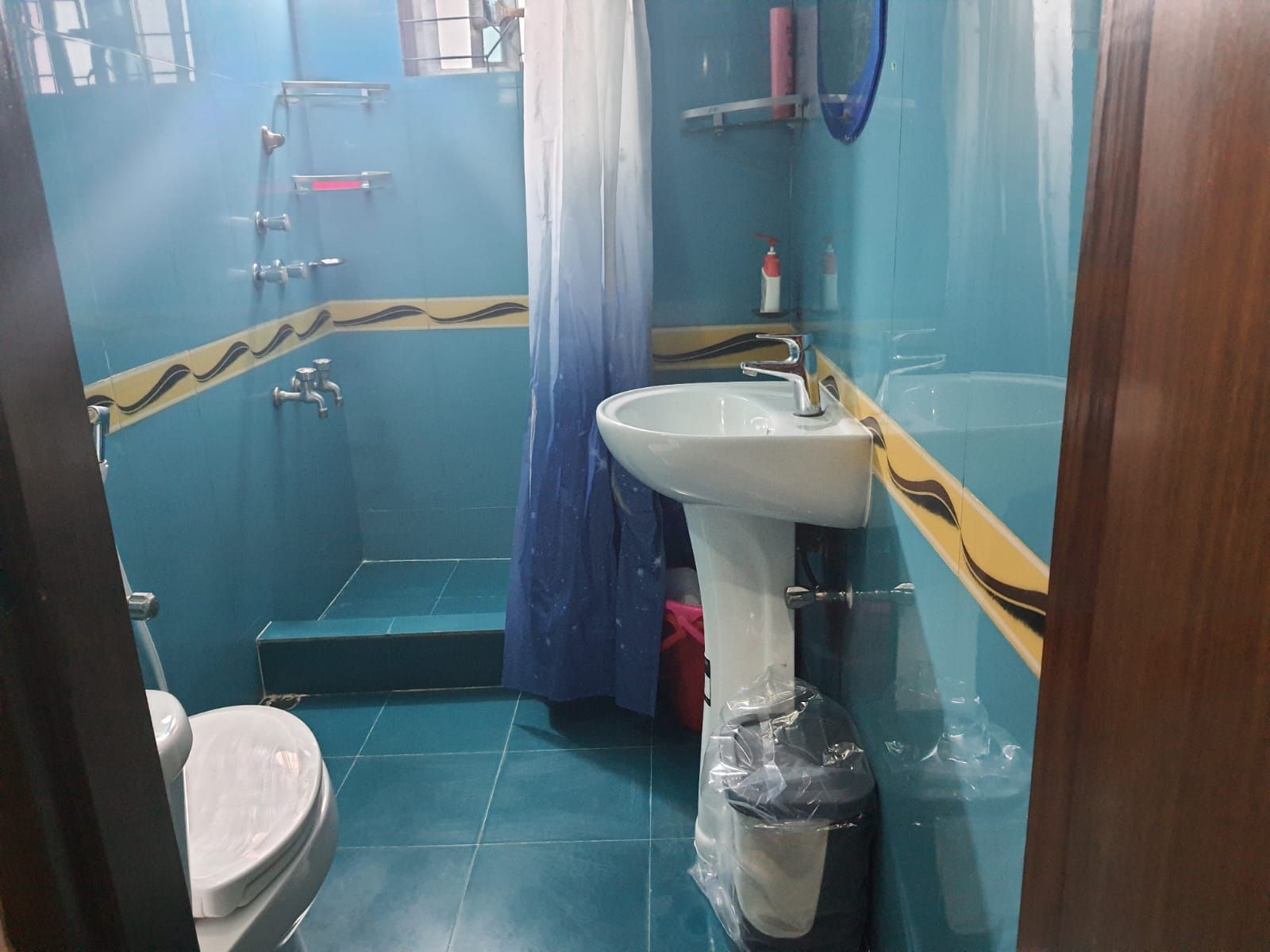 A bathroom with a toilet, sink, shower, and blue tiled walls.
