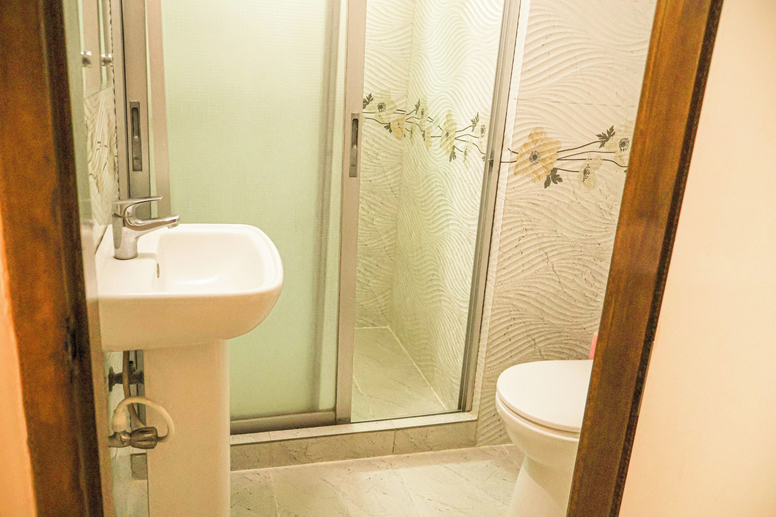 A bathroom with a white sink, a glass shower enclosure, and a toilet.